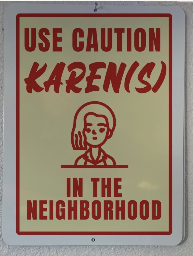Sublimated metal sign in red on cream reading Use Caution Karen(s) In The Neighborhood with an illustrated figure